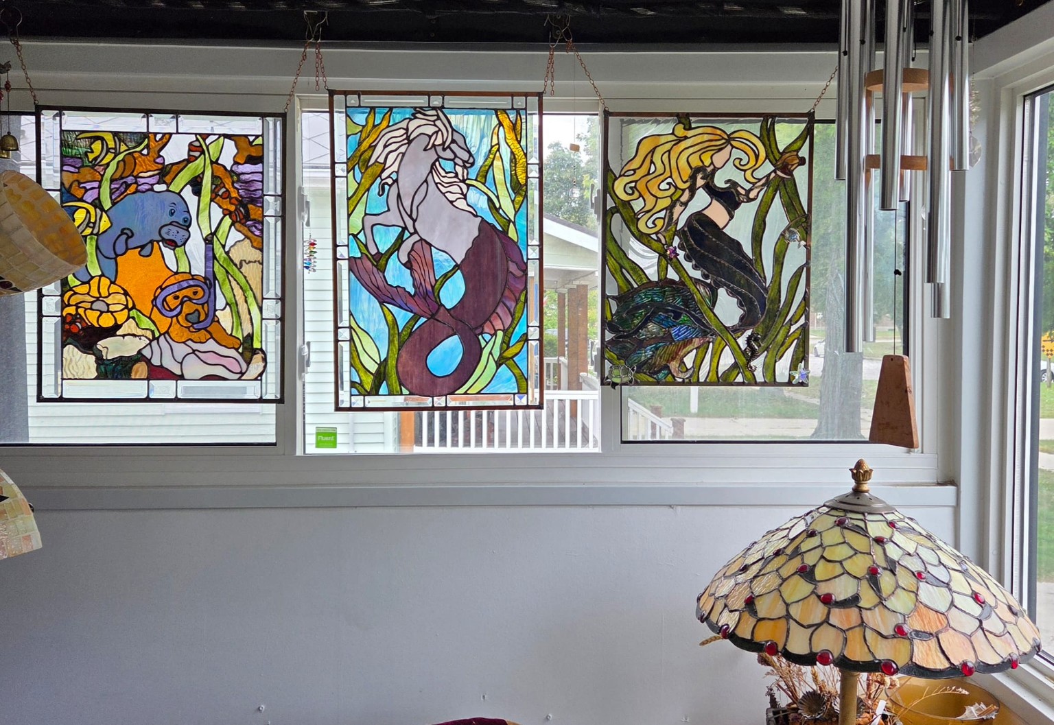 Three large imaginative stained-glass panels displayed in a window
